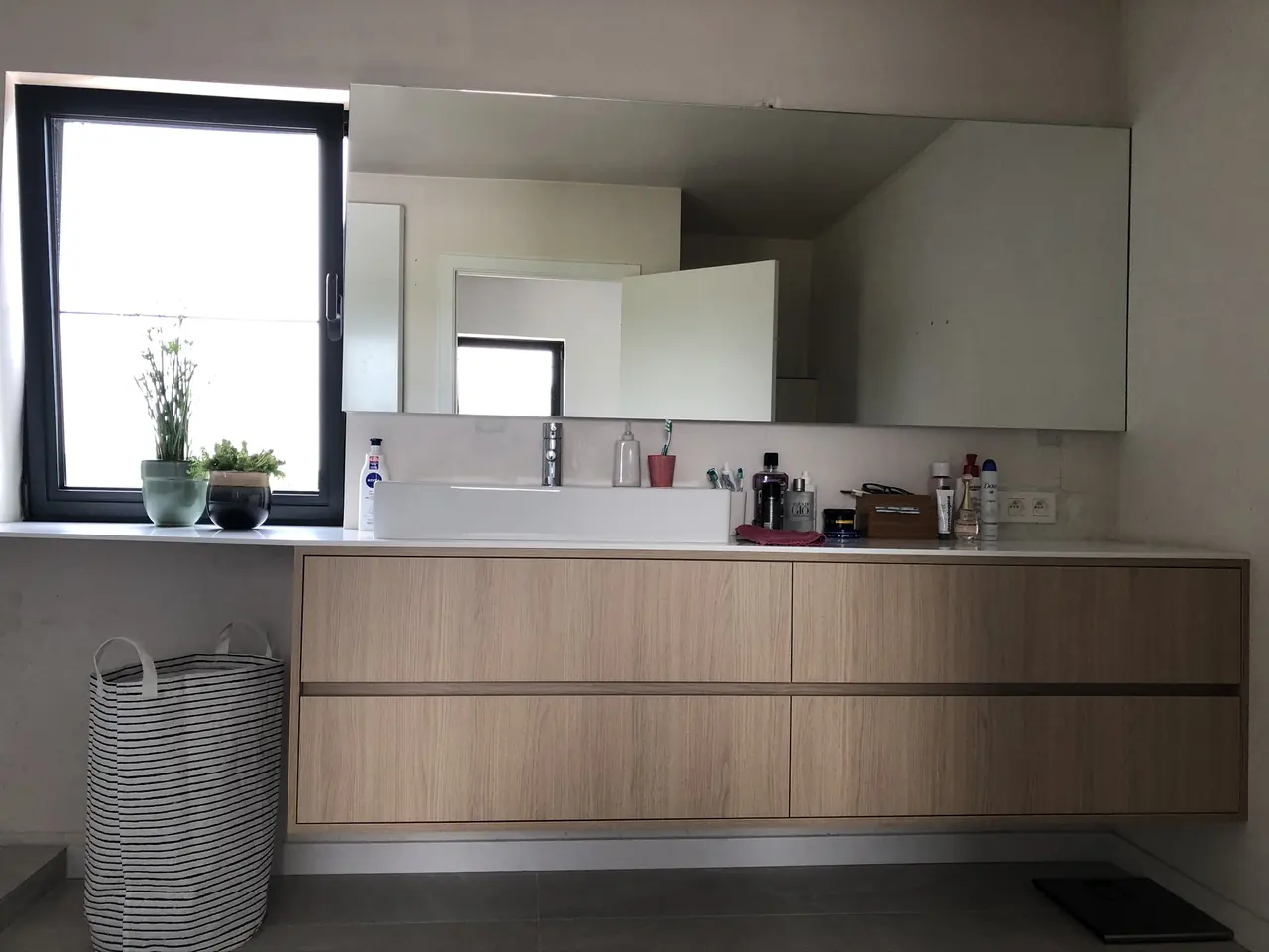 Badkamermeubel in eikenfineer onder een spiegelwand