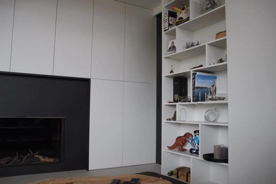 Haardwand met witte kasten en een open boekenkast