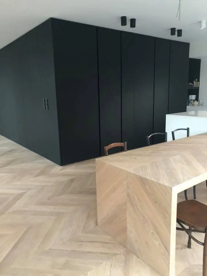 Zwart kastvolume met aansluitende eiken tafel op visgraatparket