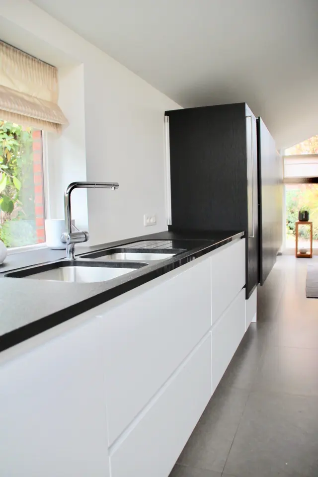 Witte keuken met zwart werkblad en hoge zwarte kast