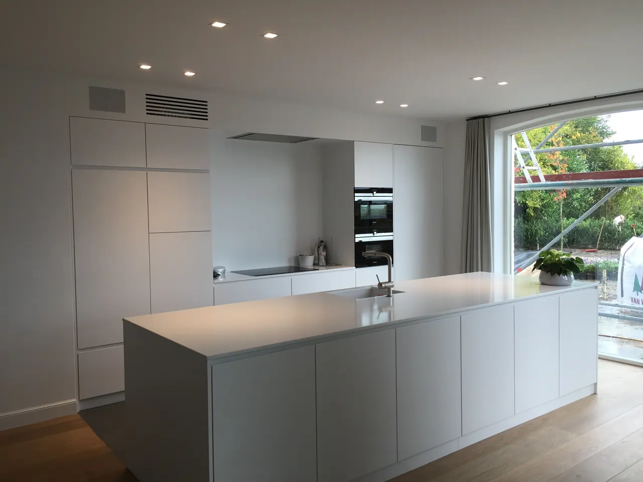 Groot wit kookeiland met hoge kastenwand