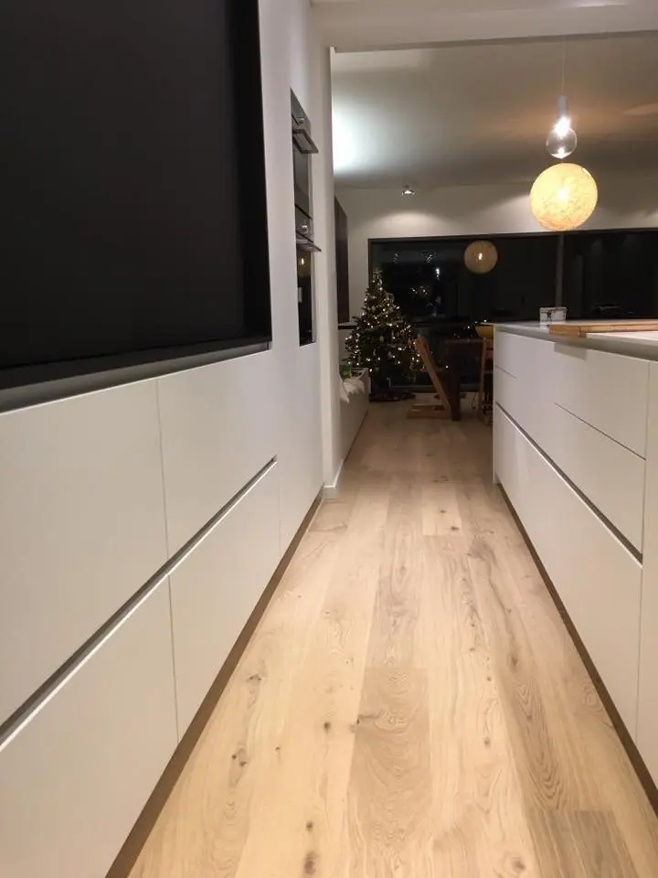Brede eiken planken langs een witte keuken