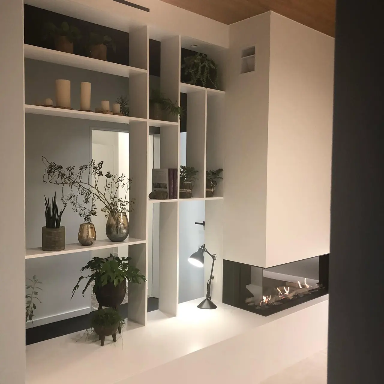 Witte open vakkenwand rond een driezijdige haard