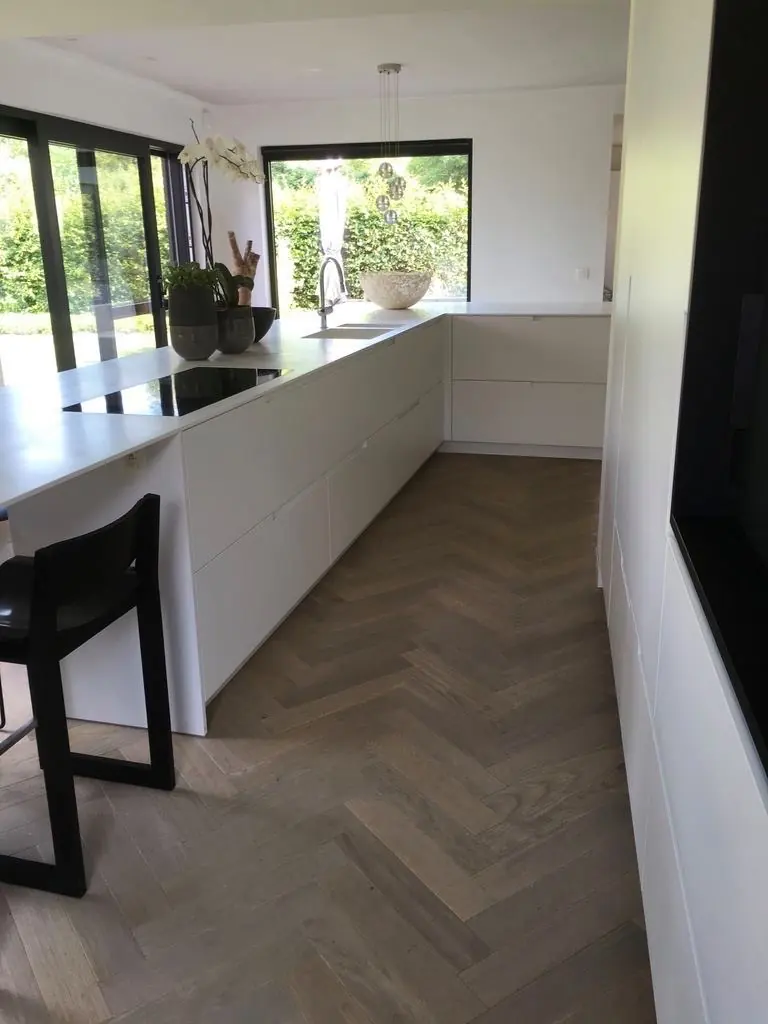 Visgraatparket in een keuken met wit eiland